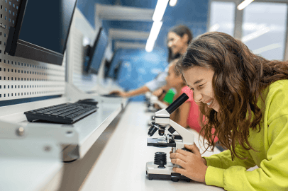 Garota de lado para a câmera olhando para o microscópio com interesse